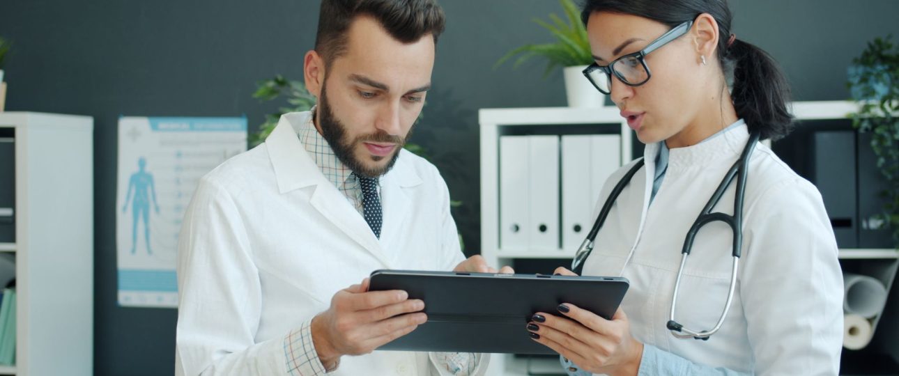 medical professionals discussing patient data on tablet